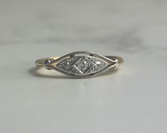 MATERIALS: Diamond, 18ct yellow gold, platinum DIMENSIONS: The entire setting is approx 15mm x 5mm. ERA/HALLMARK: .Art Deco 1930s, stamped 18ct SIZE: UK K US 5 1/4 can be resized WEIGHT: 2.31g CONDITION: Great condition, no damage or repairs. A pretty antique diamond ring set in 18ct yellow gold and platinum. This unusual ring has a setting almost like the shape of an eye, with the central diamond looking like the pupil. There are a further two small diamonds on the head of the ring in a platinu Art Deco Engagement Ring White Gold, Vintage Art Deco Rings 1920s, Art Deco Diamond Ring, Deco Diamond Ring, Diamond Dress Ring, Vintage Diamond Ring, Vintage Art Deco Rings, Diamond Dress, Unusual Rings