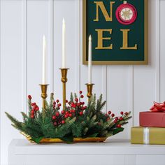 a christmas centerpiece with candles, holly and red berries