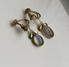 "Please check my own website at www.elegantium.co.uk for my best prices :-) A wonderful extremely rare pair of antique Arts and Crafts earrings by Liberty & Co of London, c1910. They have been crafted in 9ct gold (stamped on the screw back) and show four flashy Ceylon blue moonstones. I adore these stones and the way they flash from clear to the vibrant blue you can see in the images. A similar pair, also with a foliate design,  was sold historically at the fabulous Tadema Gallery in London. I h Antique Clip-on Earrings For Anniversary, Antique Yellow Gold Clip-on Earrings, Victorian Gold Jewelry With Moonstone, Vintage Gold Moonstone Jewelry, Victorian Gold Moonstone Jewelry, Victorian Moonstone Gold Jewelry, Antique Wedding Cabochon Earrings, Vintage Moonstone Jewelry Collectible, Sandra Brown