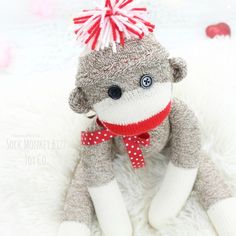 a sock monkey with a red and white bow on it's head sitting on a blanket