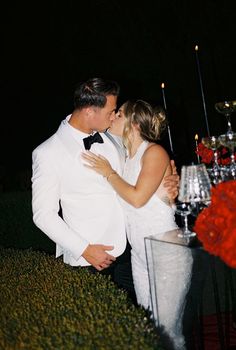 a man and woman kissing in front of a table with candles on top of it