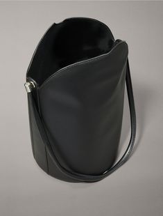 Crafted from 100% faux leather, this shoulder bag features solid, minimal styling. Designed with a top flap closure and detailed with an embossed CK monogram logo at the side. A simple silhouette, this bag is perfect for holding essentials on your evening out.  Material: 100% Polyurethane. Ck Monogram, Side A, Simple Silhouette, Monogram Logo, Bucket Bag, Calvin Klein, Faux Leather, Monogram, Shoulder Bag