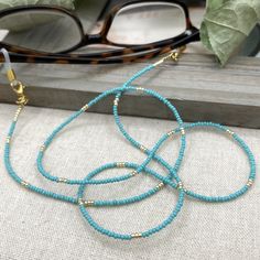 Simple and bohemian eyeglasses necklace made with Preciosa Czech crystal seed beads in Turquoise tones with tiny gold plated crystal seed beads.  Paired with delicate gold plated crystal seed beads , this handmade eyeglass chain will definitely create a unique look. This eyeglass lanyard is made on strong quality beading wire with gold plated wire guardians that protect the quality white eyeglass holder grips. The necklace is ended with spring clasps that hold the eyeglass grips and they can be Blue Glasses Chains With Colorful Beads For Beach, Blue Beaded Glasses Chain For Beach, Blue Glasses Chains For Summer Beach, Blue Glasses Chains For Beach Summer, Blue Glasses Chains For Beach In Summer, Blue Beaded Chain Glasses Chains With Round Beads, Blue Beaded Glasses Chains, Blue Glasses Chains With Colorful Beads As Gift, Blue Glasses Chains With Colorful Beads For Gift