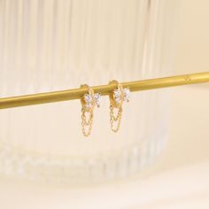 two small white diamond earrings on a gold bar