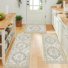 two rugs in the middle of a kitchen with wooden floors and white walls, along with an open door