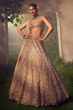 Gold attached cancan tulle lehenga embroidered with coinciding circular motifs embellished with dori and sequins work. Comes with a scallop dupatta and a plunging embroidered padded blouse.
Components: 3
Pattern: Embroidered
Type Of Work: Dori, Sequins
Neckline: Plunged
Sleeve Type: Sleeveless
Fabric: Net
Color: Gold
Other Details: 
Scalloped hem lehenga and dupatta
Back scoop neck blouse
Length:
Lehenga: 45 inches
Blouse: 14 inches
Dupatta: 3 mtrs
Occasion: Bride,Wedding - Aza Fashions Mirror Lehenga, Tulle Lehenga, Plunge Blouse, Seema Gujral, Mirror Work Lehenga, Gold Tulle, Ceremony Dress, Net Lehenga, Embroidered Lehenga