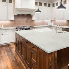 a large kitchen with white cabinets and wooden floors