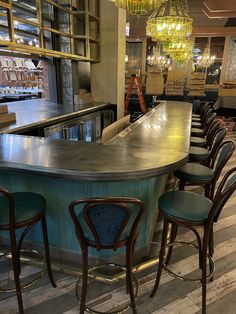 an empty bar with several stools in front of it and a chandelier hanging from the ceiling