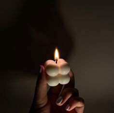 a person holding a lit candle in their hand with the light shining on her face