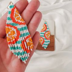 someone is holding some beaded earrings in their hand and it looks like they are made out of beads