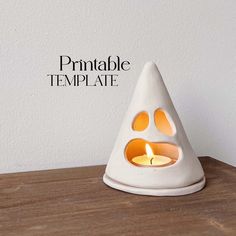 a small white candle holder with an animal paw print on the front and side, sitting on a wooden table