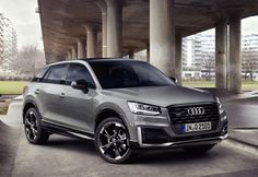 an audi suv is parked in front of a parking garage with columns and concrete flooring