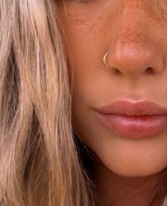 a close up of a woman with freckles on her nose and nose ring