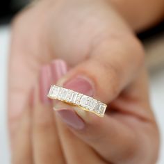 a woman's hand holding a gold ring with three baguettes on it