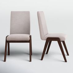 two chairs side by side, one is beige and the other has brown wood legs