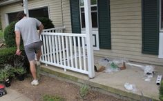 a man standing on the front porch of a house next to a white picket fence