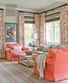 a living room filled with lots of furniture and windows covered in orange drapess