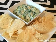 spinach dip and tortilla chips on a plate with black and white cheddar