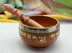 a small singing bowl with a wooden stick sticking out of it