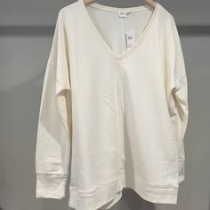 New W Tags, Never Worn, Gap V-Neck Sweatshirt, Off White Color, Large And Loose Fitting. A Seam Runs Along The Bottom, Along The Cuffs, And Down The Middle Of The Front And Back To Add Dimension. Spring V-neck Sweatshirt For Loungewear, White Cotton V-neck Top For Everyday, Casual Cream V-neck Top, Oversized V-neck Sweatshirt Casual, Oversized V-neck Sweatshirt Casual Style, Casual Oversized V-neck Sweatshirt, Oversized V-neck Sweatshirt For Spring, Oversized Cotton V-neck Sweatshirt, Oversized V-neck Sweatshirt For Layering