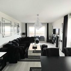 a black and white living room with couches, coffee table and chandelier