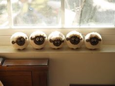 four stuffed sheep sitting on top of a window sill