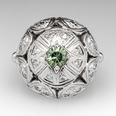 This vintage ring features a domed gallery with a pierced design that is accented with one (1) prong set, round modified brilliant natural Demantoid garnet and twenty-four (24) bead set, round single cut diamonds. The ring measures 17.8mm at the top, rises 9.3mm above the finger, tapering to 1.8mm wide and 1.1mm thick at the base of the shank. It is crafted in 14k white gold and is currently a size 5.25. Several diamonds have light unnoticeable chips. Vintage Green Diamond Platinum Ring, Vintage Green Diamond Ring In Platinum, Art Deco Emerald Ring With 17 Jewels, Green Art Deco Diamond Ring With Diamond Cut, Heirloom Green Diamond Ring With Diamond Cut, Antique Green Oval Diamond Ring, Antique Green Diamond Ring With Center Stone, Vintage Green Diamond Ring With Center Stone, Gemstone Dome Ring For Wedding