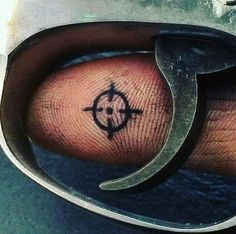 a person with a compass tattoo on their left hand holding a pair of scissor