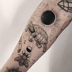 a black and white tattoo on the arm of a person with a sun, moon and two bees