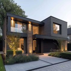 a modern house is lit up at night with lights on the front and side windows