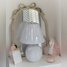 a white lamp sitting on top of a table next to a mirror and other items