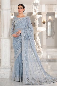 Our contemporary saree rendered in hues of ice blue with a beaded neckline and embellishments of pearls, diamonties, sequins along 3D floral accents and jaal spread with intricate cutwork detailing and pearls finishings. CUT: Saree Maria B Saree, Ice Blue Saree, Saree Net, Contemporary Saree, Fancy Sarees Party Wear, Maria B, Net Saree, Pakistani Wedding Dresses, Bridal Party Dresses