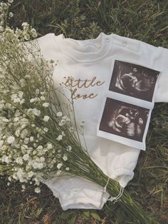 a baby's bodysuit laying on the ground next to flowers and an x - ray