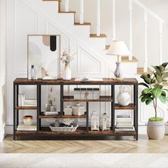 a living room with white walls and wooden flooring next to a stair case filled with books