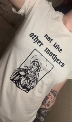 Elevate your style with our exclusive "Not Like Other Mothers" tee showcasing unique artwork of a captivating, gothic, witchy interpretation of Mother Teresa. Stand out from the crowd with Dark Majesty's distinctive apparel, designed for goth and alternative parents, as well as individuals of all backgrounds! White Gothic T-shirt For Streetwear, White T-shirt For Alternative Fashion, Cotton Tops With Custom Band Artwork, Gothic Tops With Letter Print, Gothic Graphic T-shirt For Streetwear, Gothic Graphic Print T-shirt For Streetwear, Gothic Graphic Print Tops For Streetwear, Cotton T-shirt With Front Print For Alternative Fashion, Gothic T-shirt With Graphic Print