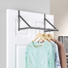 two shirts hanging on a clothes rack in front of a white door with a heart sticker above it