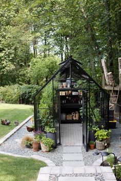 an outdoor garden with lots of potted plants and pots on the ground in front of it