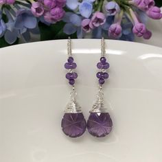 The Wisteria Path earrings weave a delicate story of rich blooms and delicate petals. These earrings feature beautiful, tender purple amethyst that have been intricately hand-carved with a unique starburst pattern and wrapped with fine sterling silver. Gracefully suspended from marquise French ear wires that are embellished with blossoms of petite, micro-faceted amethyst. Swirled, vine-like detailing on the ear wires give an extra feminine touch to these lovelies. Very lightweight, unique and oh Handmade Lavender Crystal Drop Earrings, Lavender Amethyst Earrings With Natural Stones, Lavender Amethyst Teardrop Earrings, Elegant Purple Wire Wrapped Crystal Earrings, Purple Long Drop Earrings With Natural Stones, Lavender Amethyst Earrings With Ear Wire, Lavender Amethyst Drop Earrings, Lavender Amethyst Dangle Earrings, Purple Amethyst Long Drop Earrings