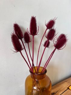 a vase filled with red flowers sitting on top of a wooden table next to a white wall