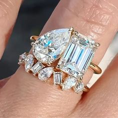 a woman's engagement ring with an emerald and diamond set on her finger,