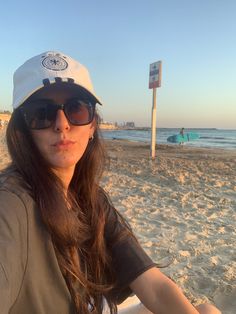 a woman sitting on top of a white surfboard next to the ocean in front of a beach