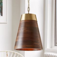 a wooden lamp hanging from a ceiling in a room with white walls and chairs around it