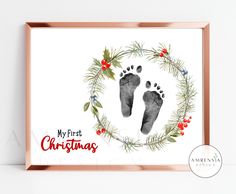 a christmas card with the words, my first christmas and an image of two feet in a wreath