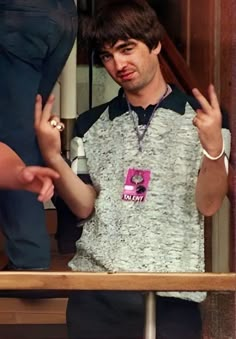 a man standing in front of a wooden table holding his hand up to the camera