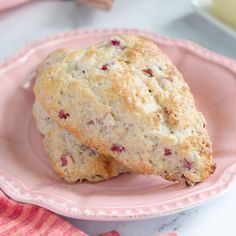 two scones on a pink plate next to a glass of milk