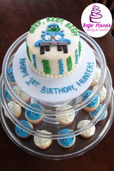 a birthday cake with blue and green frosting sitting on top of cupcakes