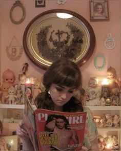 a girl reading a magazine in front of a wall with teddy bears