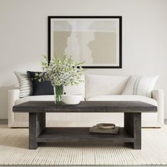 a living room with a white couch, coffee table and flowers in vases on it