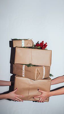 two women holding wrapped presents in their hands by the christmas tree on top of them