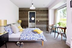 a bedroom with wood paneling and blue bedding in the center, yellow throw pillows on the foot board